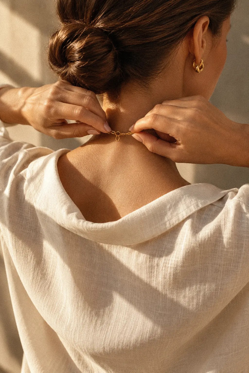 Hands with gold rings against a cream blouse