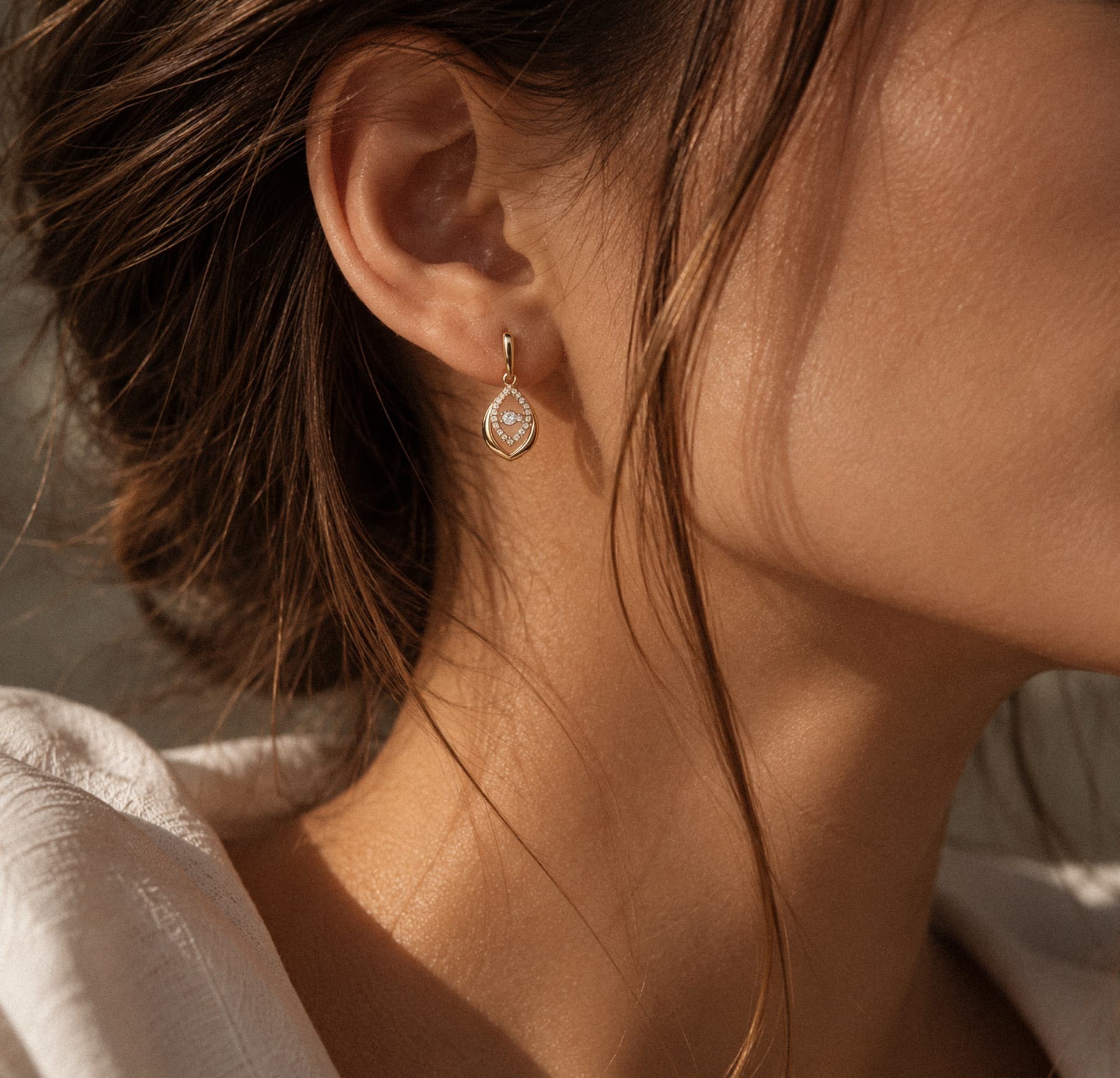 Profile of a model wearing a drop earring, close-up